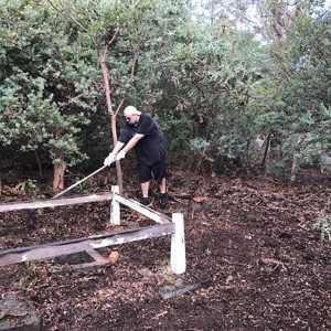 Matt Woods does a Time Team impersonation, carefully uncovering a forgotten trig point. Image Credit: Julie Matthews