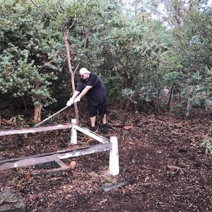 Matt Woods does a Time Team impersonation, carefully uncovering a forgotten trig point. Image Credit: Julie Matthews